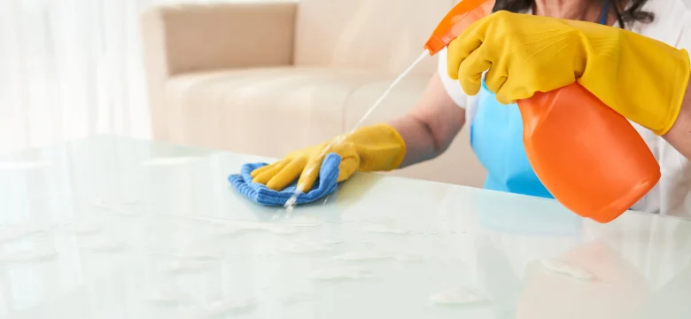 Professional cleaner spraying detergent on coffee table